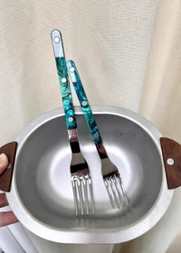 Modern elegant terra flatware pieces lying side by side on dark stone surface