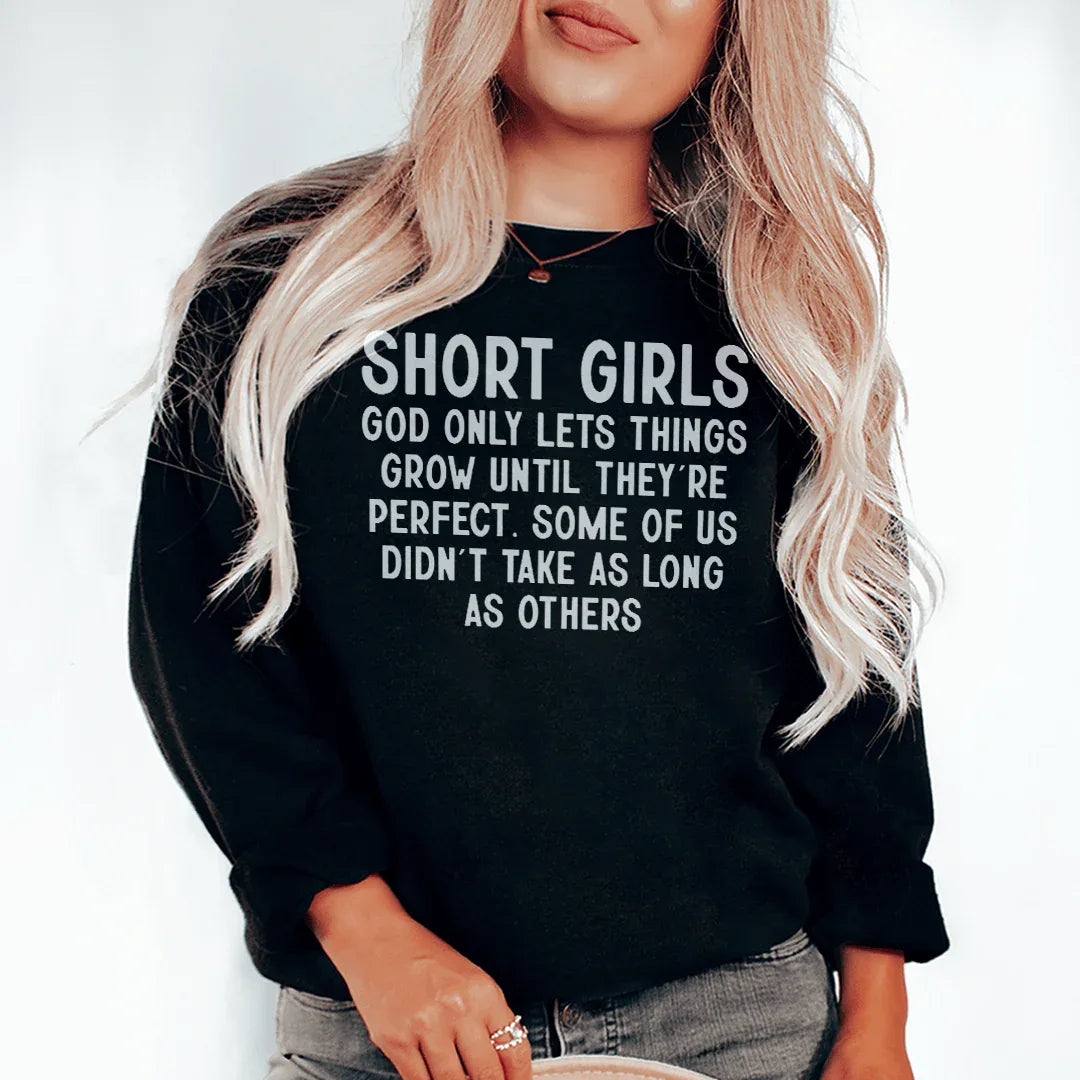 Black sweatshirt with text 'Short Girls God Only Lets Things Grow Until They're Perfect' in white font