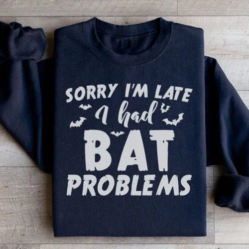 Close-up of black sweatshirt featuring Sorry I'm Late I Had Bat Problems text in white.