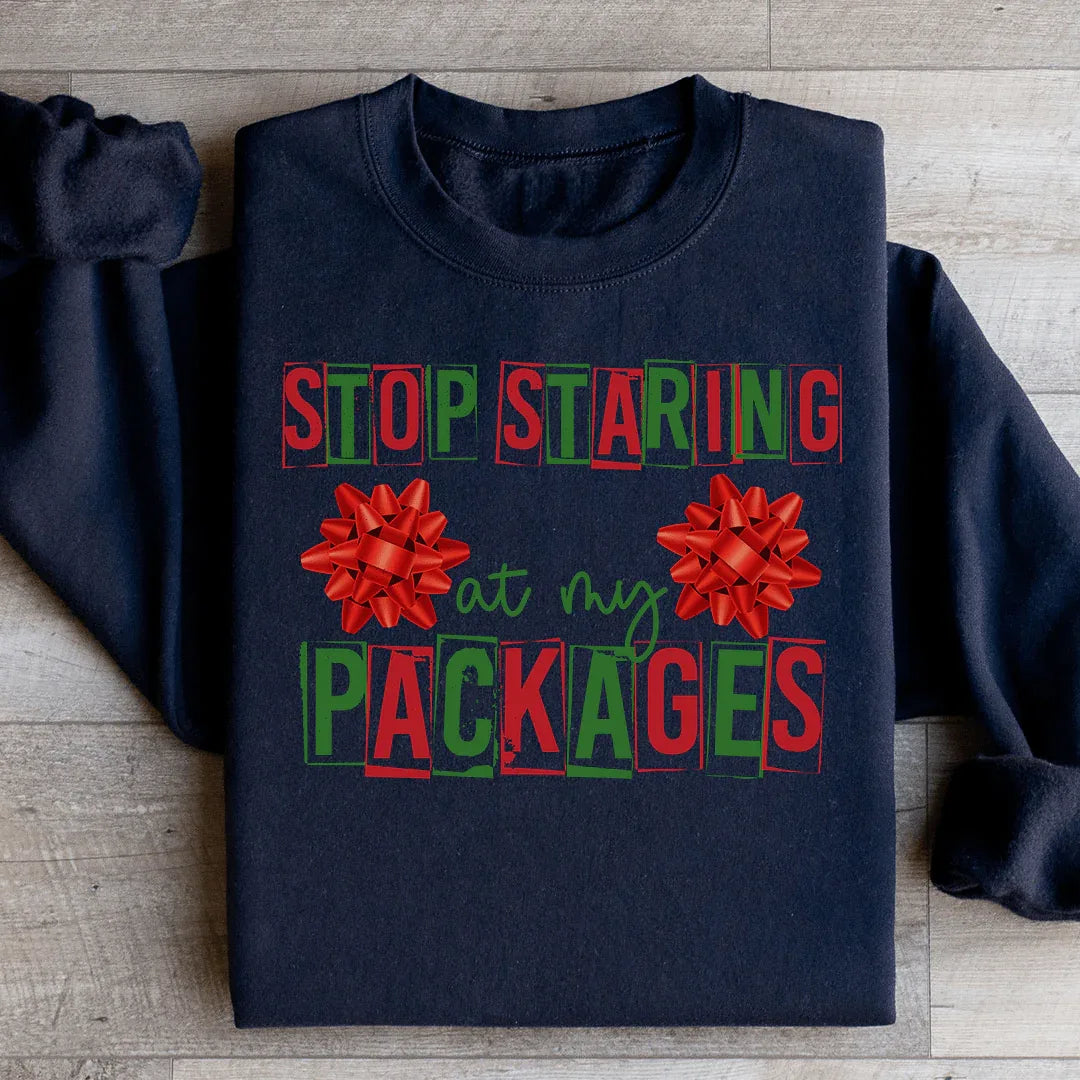 Black sweatshirt with white text saying 'Stop Staring At My Packages' in casual font.