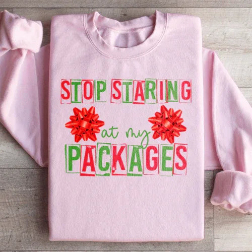 Light pink sweatshirt with 'Stop Staring At My Packages' printed in white font on front.