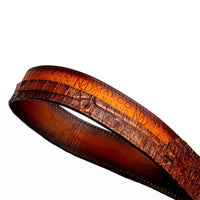 Side angle of aged brown Texas Belt focusing on buckle and embossed branding on leather.