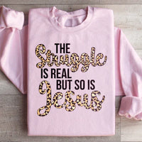 Light pink sweatshirt with large white text saying 'The Struggle Is Real But So Is Jesus'.