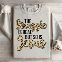 Sand-colored sweatshirt featuring bold white text stating 'The Struggle Is Real But So Is Jesus'.