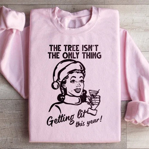 Light pink sweatshirt displaying 'The Tree Isn't The Only One Getting Lit This Year' in stylish text.