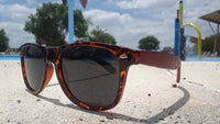 Close-up of tortoise frame sunglasses showing detailed artisan engraving on the temples.