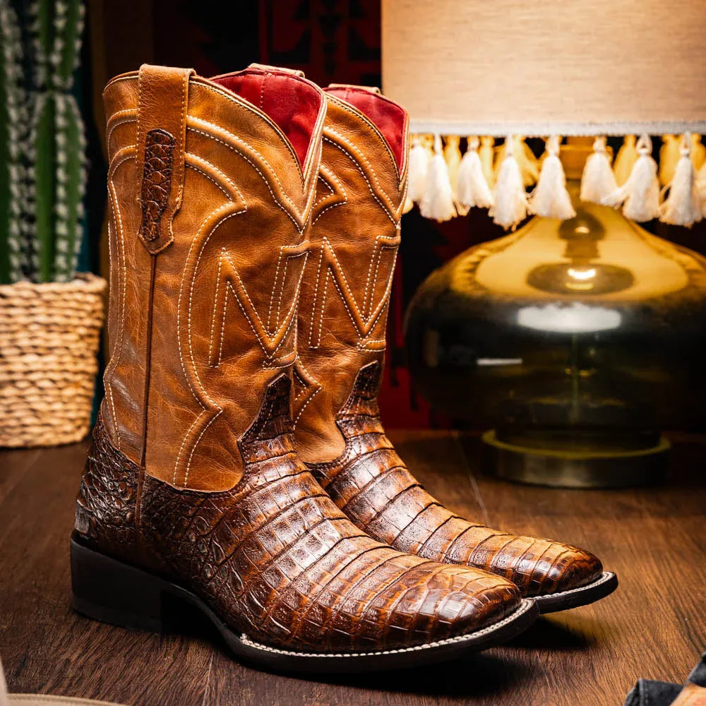 Lifestyle image of man wearing Tucson caiman belly skin cowboy boots with jeans outdoors.