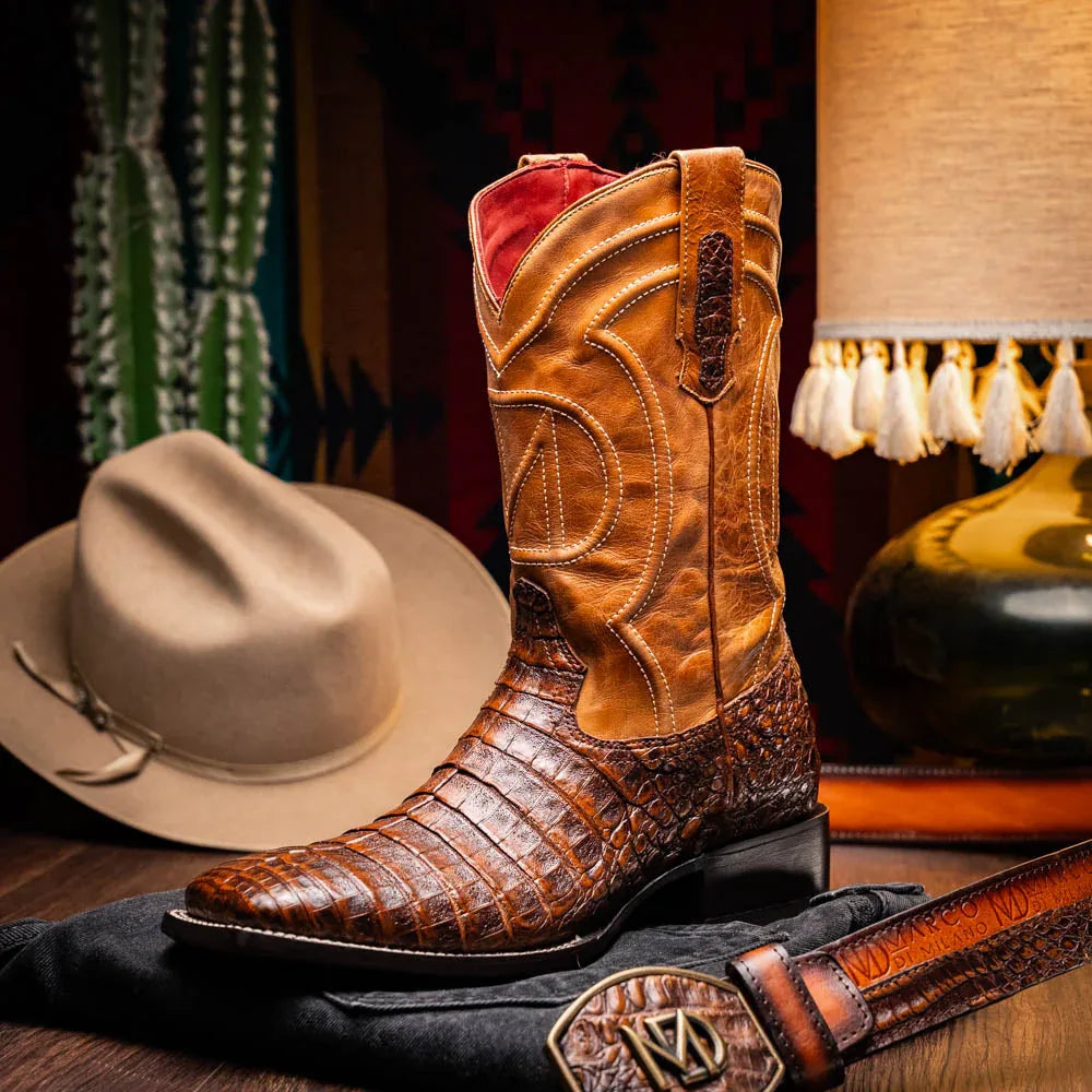 Man wearing Tucson aged maple caiman cowboy boots standing on wooden floor, showcasing boot style.