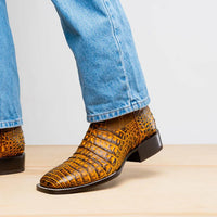 Side view of Tucson Mustard Brown boot worn with blue jeans outdoors on a stone surface.