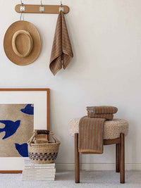 Vintage style striped bath towel hanging on a silver hook against a white tiled bathroom wall.