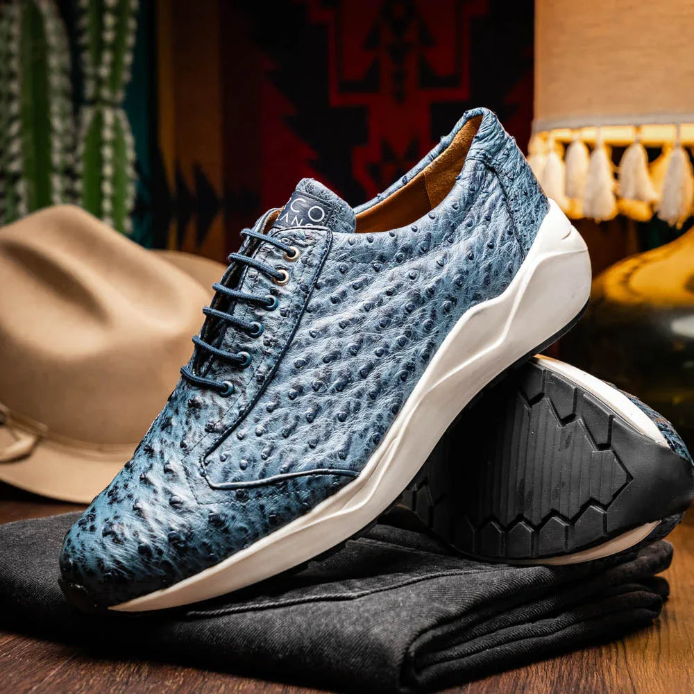 Person sitting on steps wearing stylish navy ostrich leather sneakers with white rubber soles.