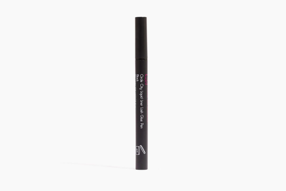 Hand holding Circle City Liquid Liner Lash Glue Pen with black cap, angled to show sleek pen design.