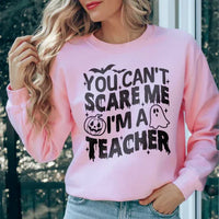 Light pink sweatshirt featuring white text 'You Can't Scare Me I'm A Teacher' on front.