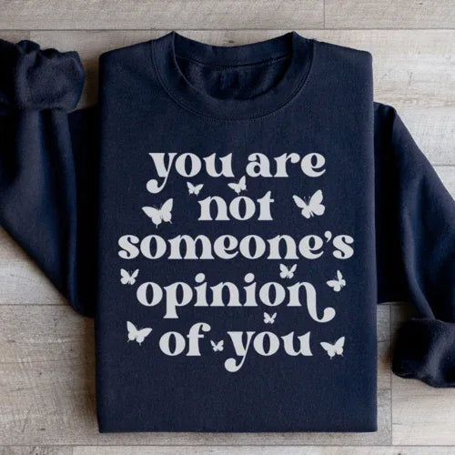 Front view of peach sweatshirt featuring the positive, empowering quote in simple typography.
